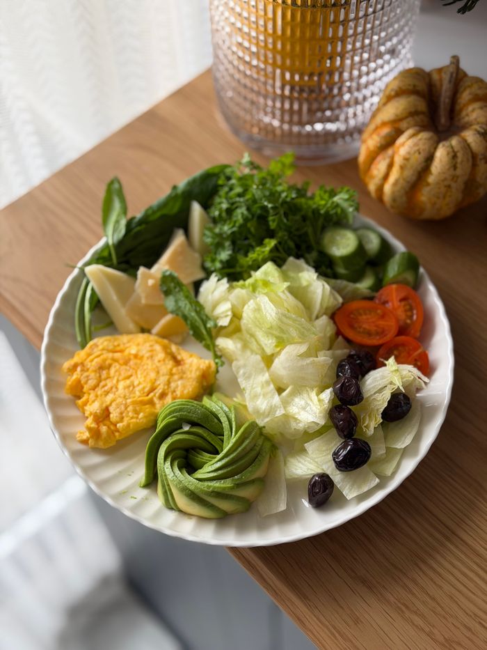 A vibrant plate featuring cheese, avocado, olives, tomatoes, and greens, perfect for a healthy breakfast.